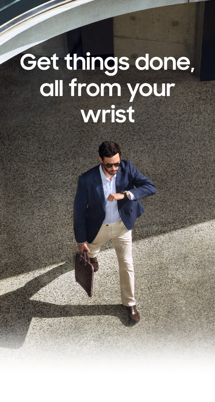 Person in a business casual outfit is looking at his Galaxy Watch8 Classic while walking.